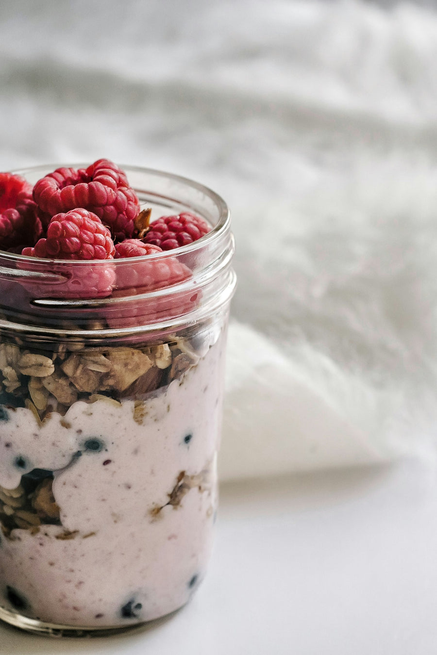 Parfait de coco fermentado con granola y frutos rojos en un tarro de cristal
