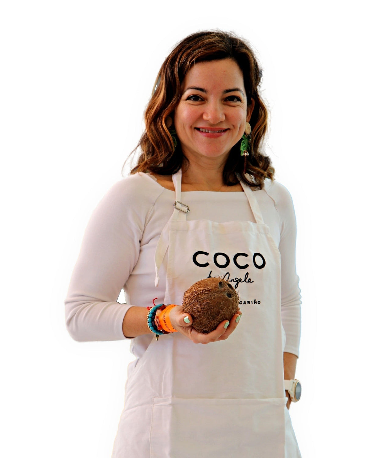 Ángela, fundadora de COCO by Angela, con el delantal de la marca y un coco entre las manos