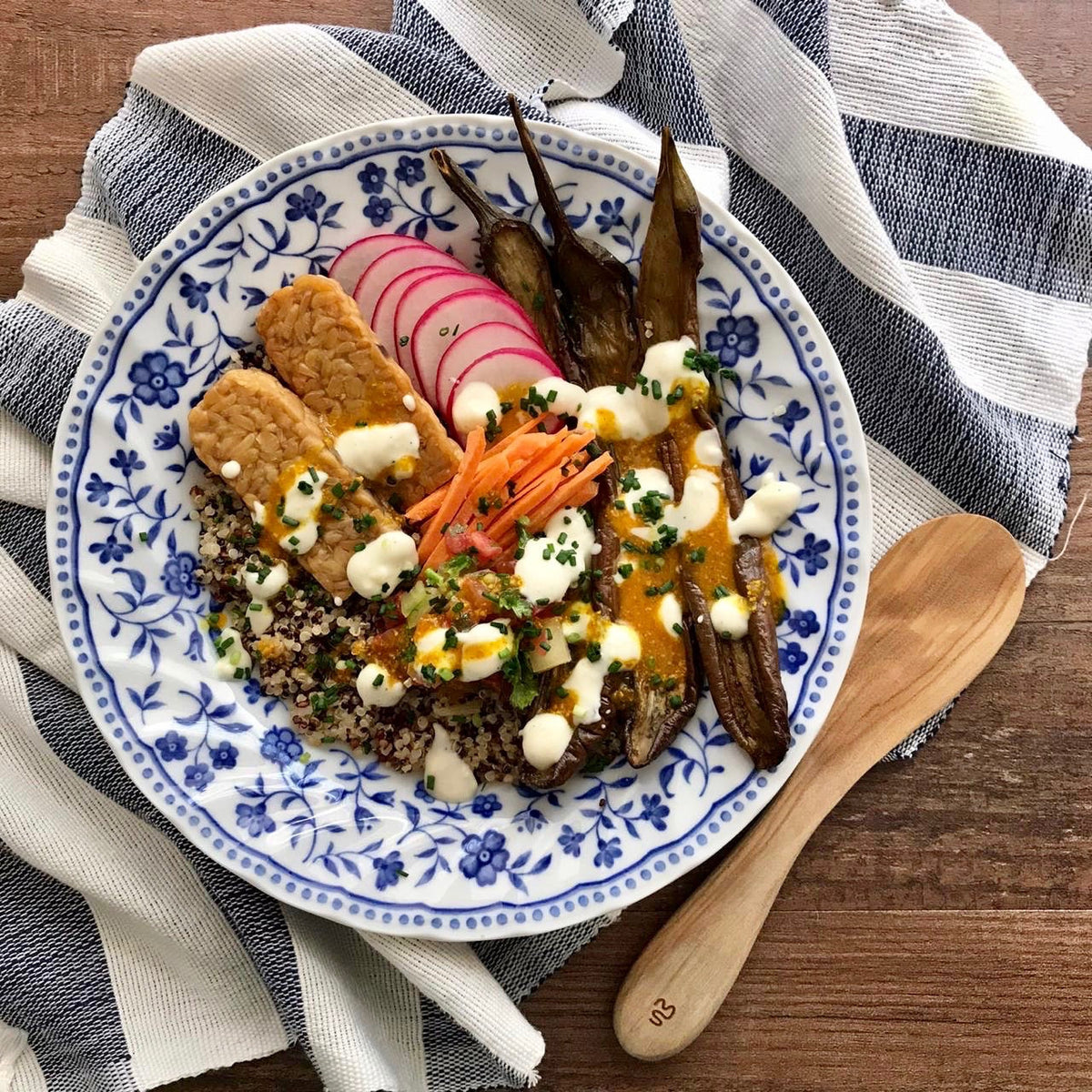 Plato de quinoa con tempeh, berenjenas asadas, rabanitos y salsa de coco fermentado COCO by Angela con cebollino