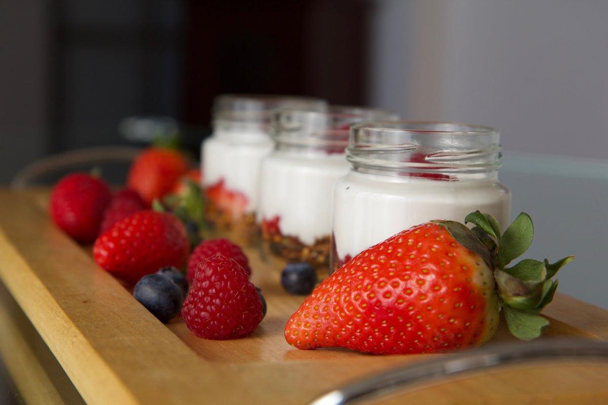 Tarros de coco fermentado cremoso con fresas, frambuesas y arándanos, alternativa vegetal al yogur