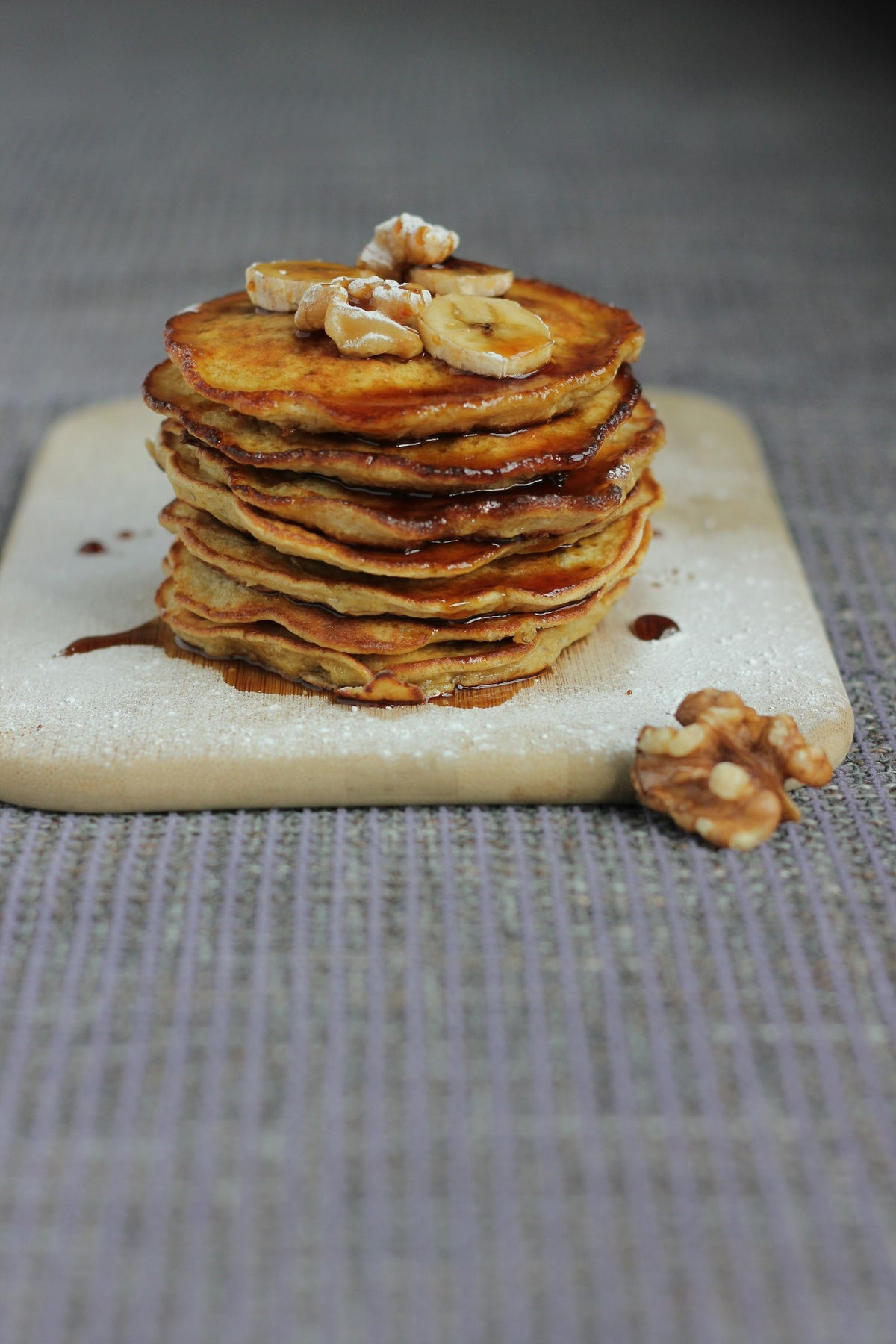 Pila de panqueques de plátano dorados con rodajas de plátano y nueces