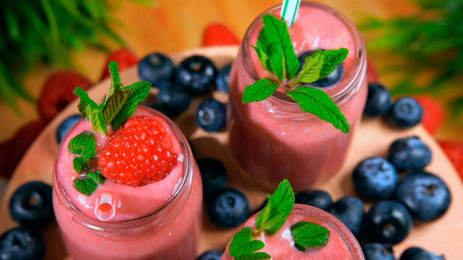 Vaso de smoothie de fresa con fresas frescas al lado