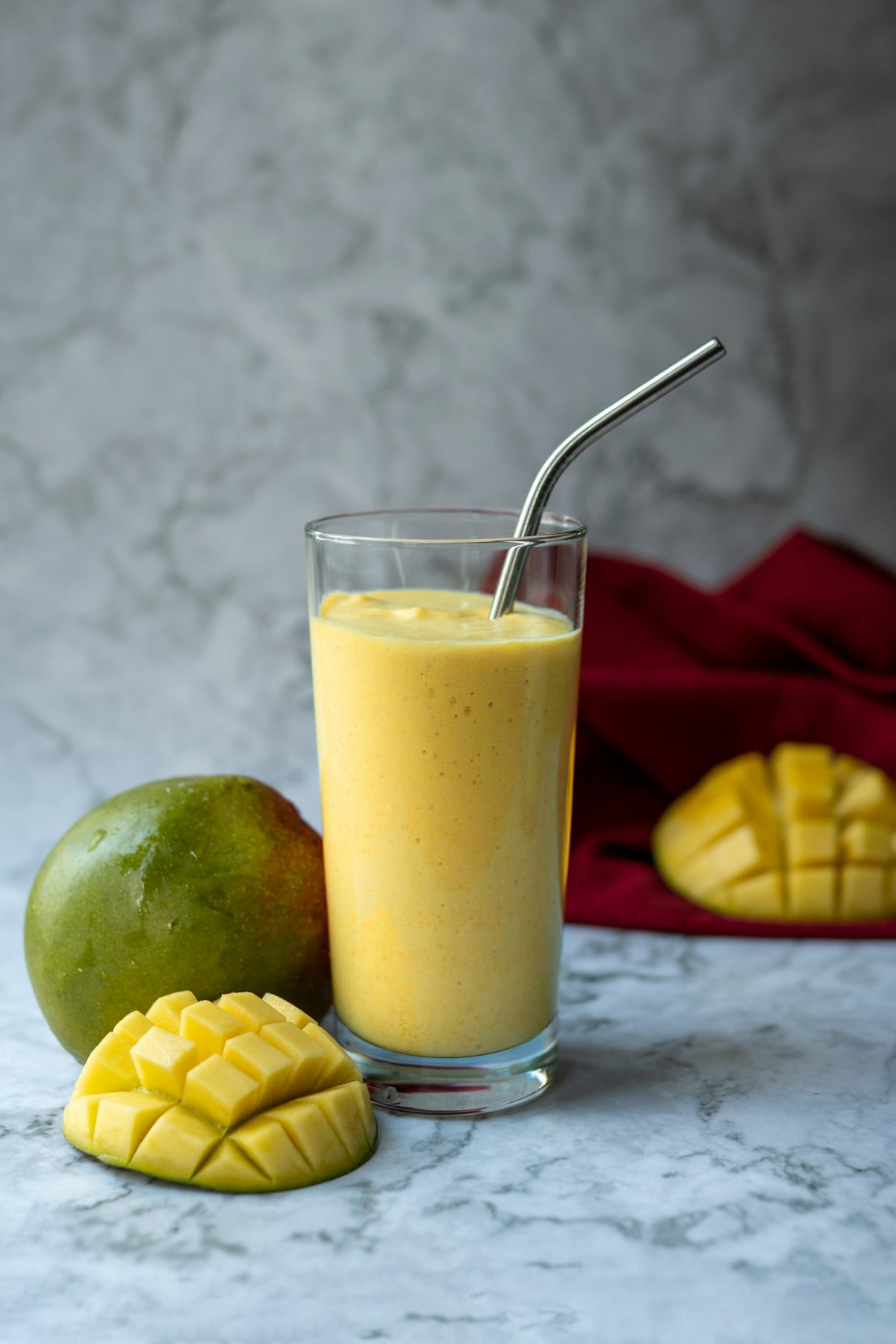 Batido de mango y maracuyá en un vaso junto a un mango