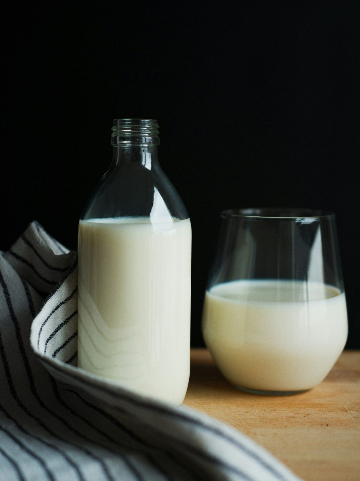 Una botella y un vaso de leche sobre una mesa de madera