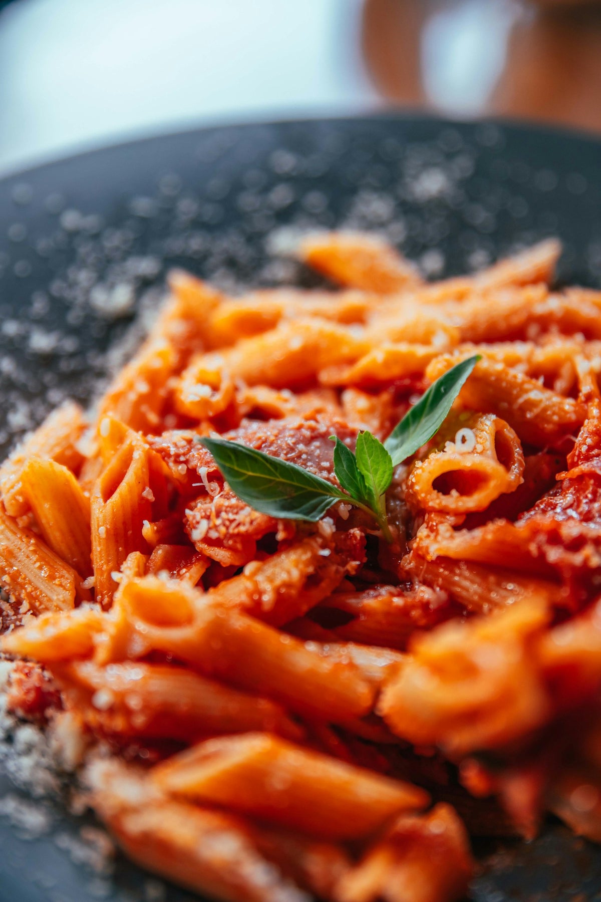 Pasta corta con salsa cremosa de tomate y una hoja de albahaca