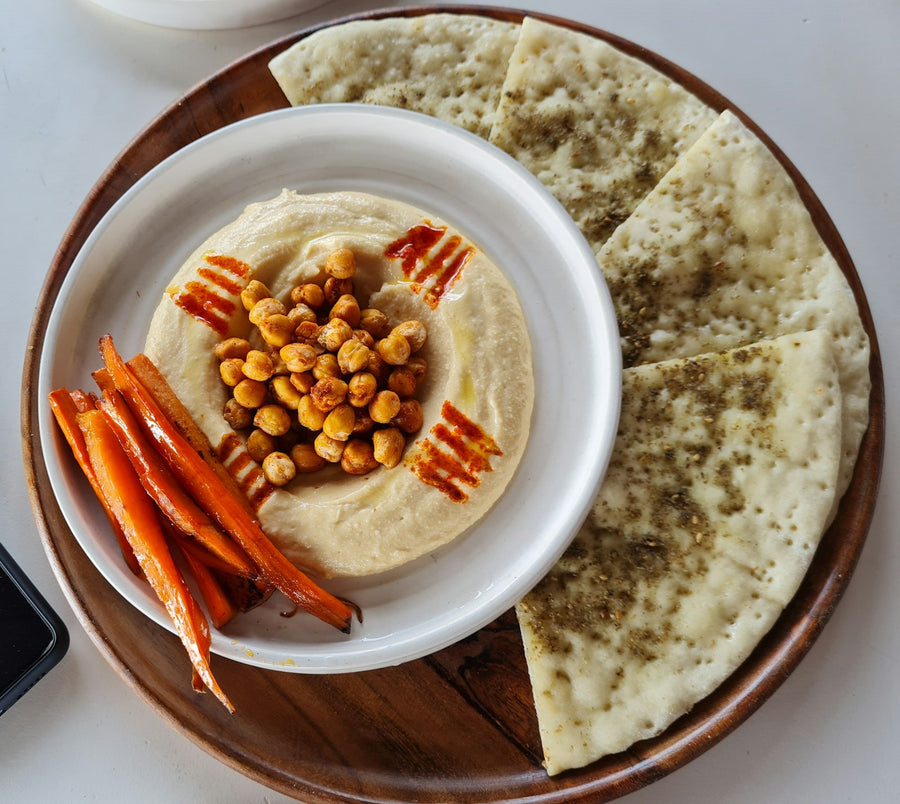 Panes planos con hummus cremoso y zanahorias frescas
