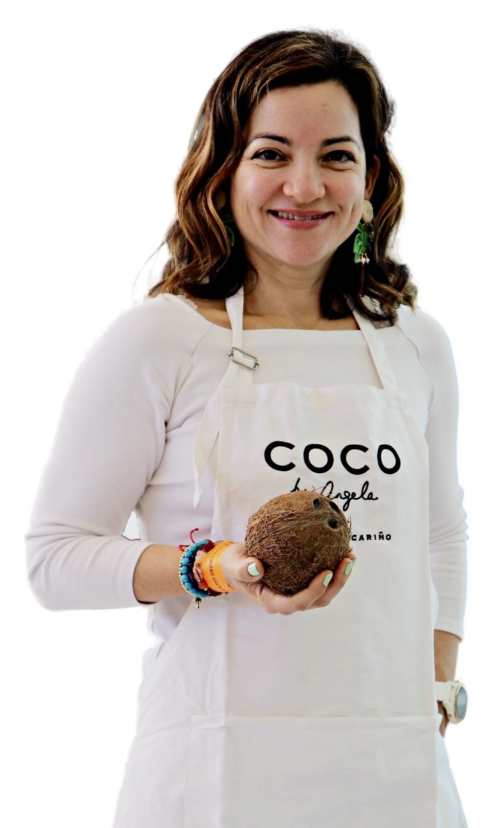 Ángela, fundadora de COCO by Angela, sonriendo con el delantal de la marca y sosteniendo un coco entre las manos, sobre fondo blanco